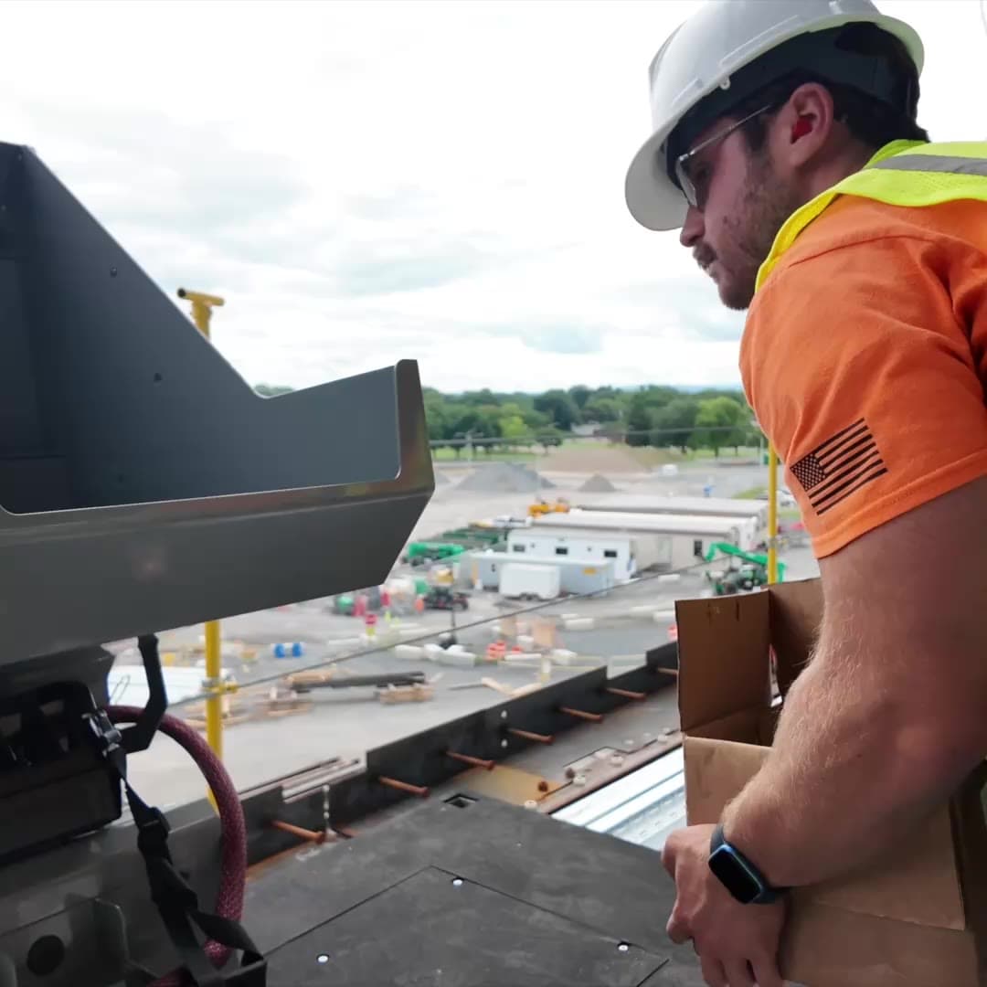 Operator lifting a box of studs into the Stud Caddy hopper