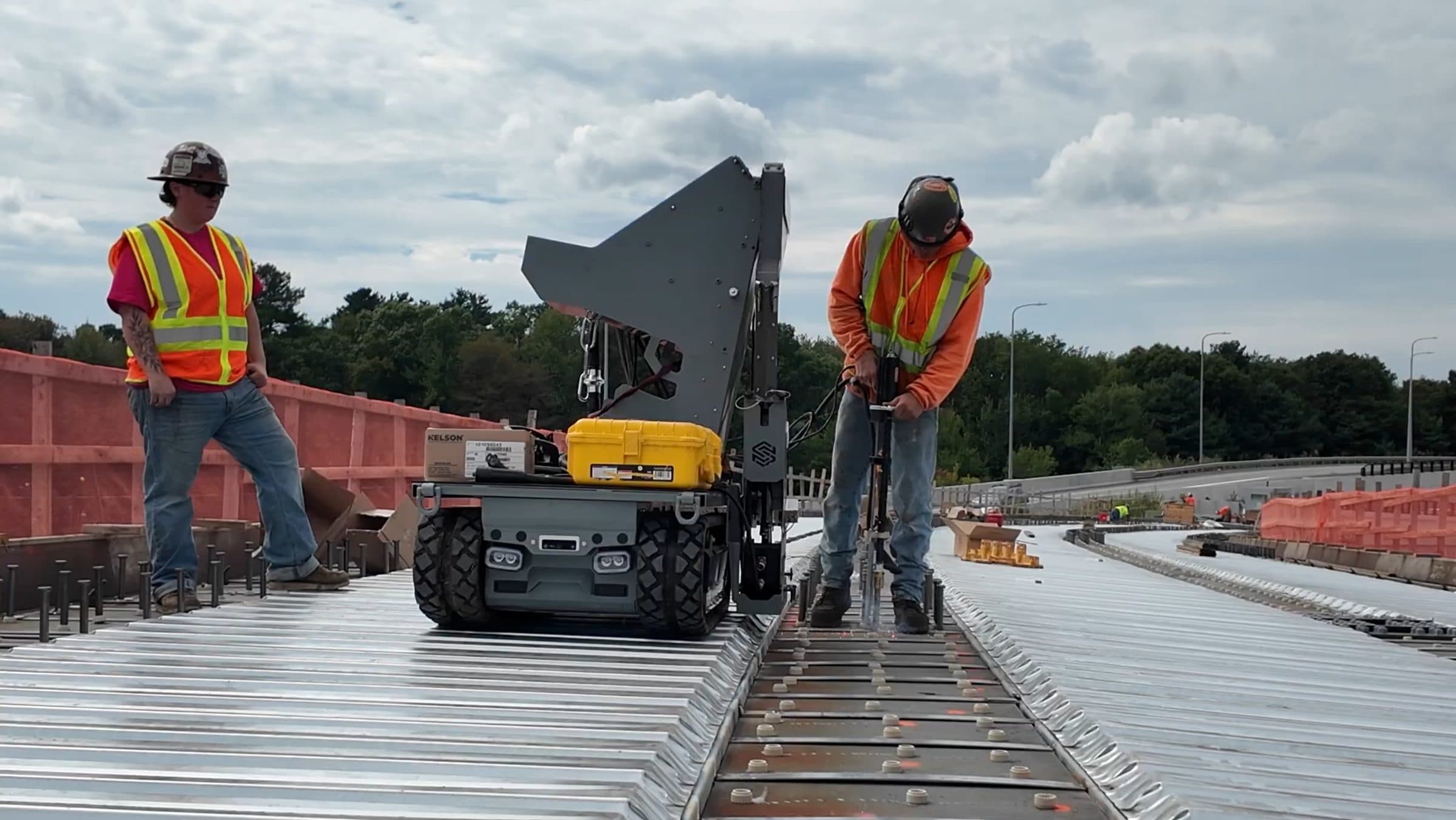 Two crew members with Stud Caddy on the I-90 overpass deck, one welding a stud